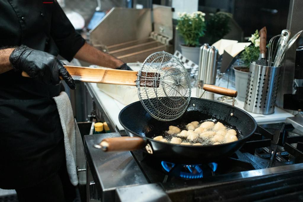 person holding a spider strainer while frying food